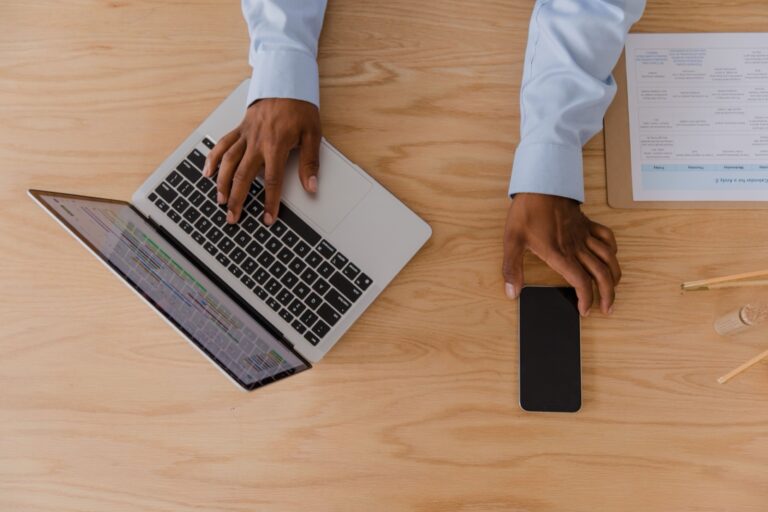 Vista superior de una persona trabajando con un portátil y un teléfono móvil sobre una mesa