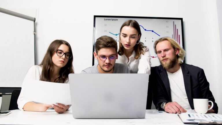 Profesionales revisando juntos la información de un portátil durante una reunión