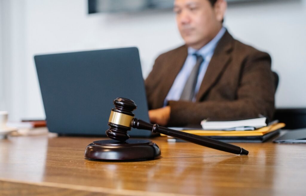 Profesional trabajando en un portátil en un despacho, con documentos y un mazo sobre la mesa
