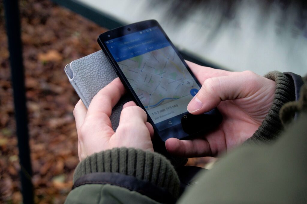 Manos consultando una aplicación de mapas en un teléfono móvil al aire libre